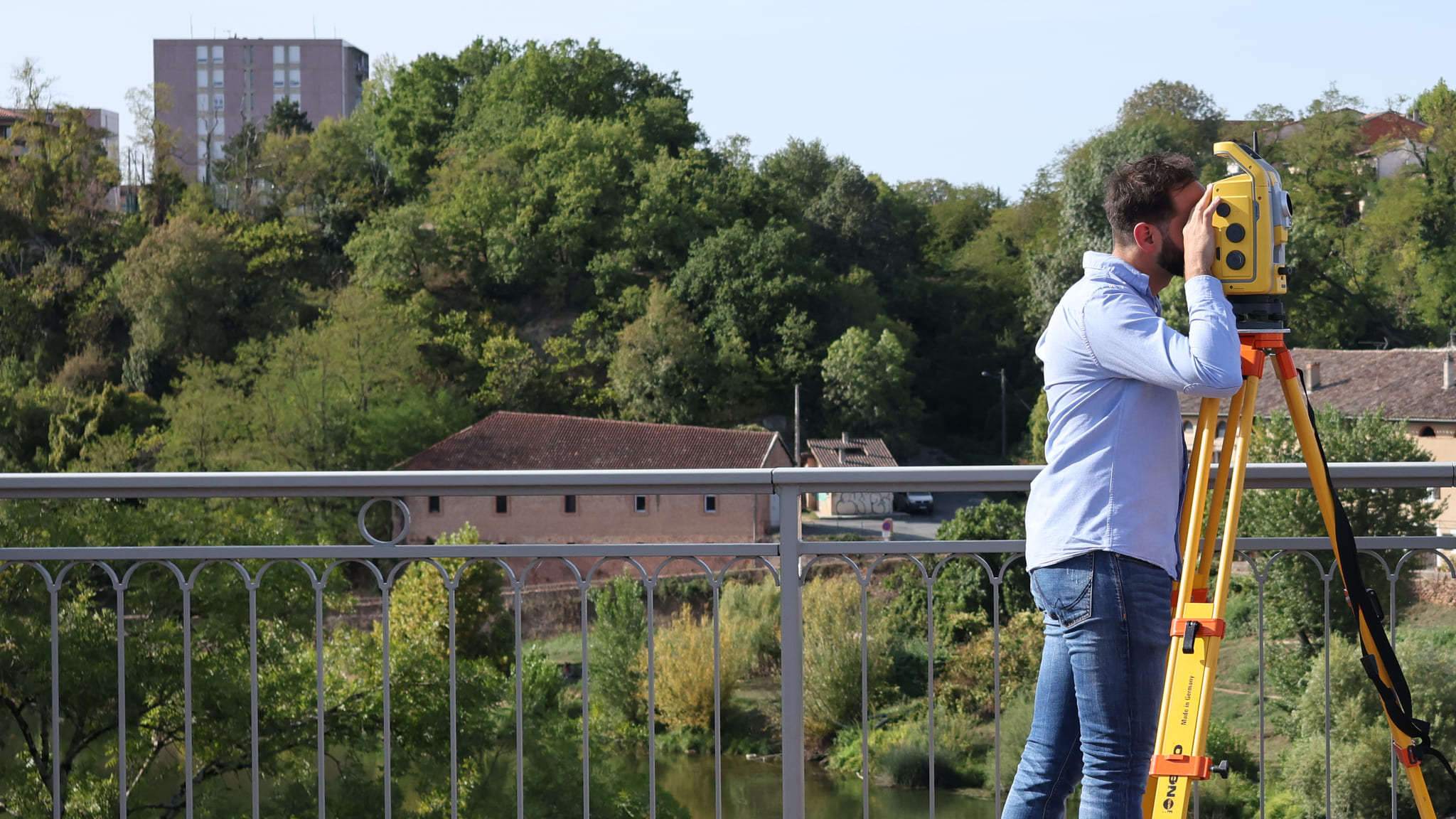 Rémy Escaffit, géomètre-expert, visant à la station totale depuis le pont de Gaillac, au-dessus du Tarn